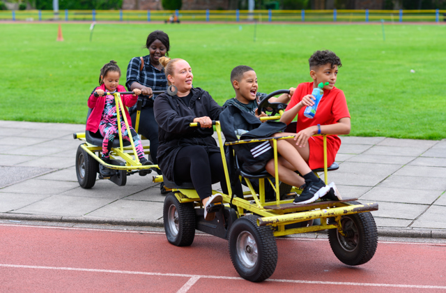 Group of children and young adults on large multiple person bicycles