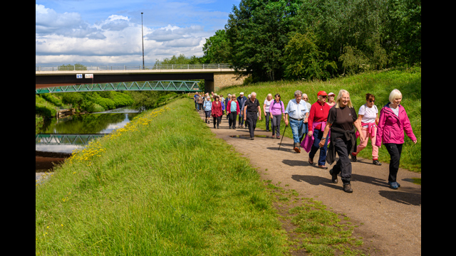 Large group walk along the bank of a river