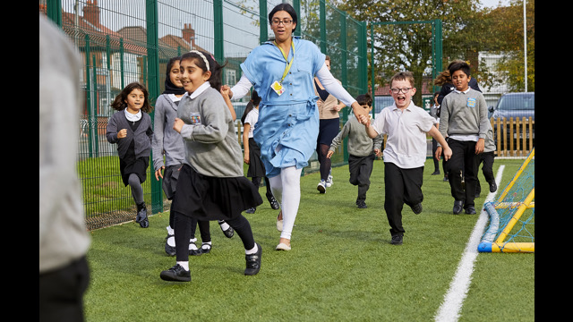 Teacher and schoolchildren running around taking part in The Daily Mile