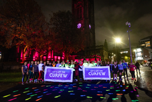 Group of runners with Lets Lift the Curfew banners and UV footprints